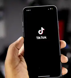 H?nd som holder telefon med tiktok-logoen p? skjermen